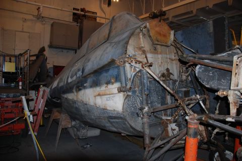 1996 Ford Bronco - The heavily corroded fuselage of an aircraft sits in a workshop, showing signs of extensive wear and tear.