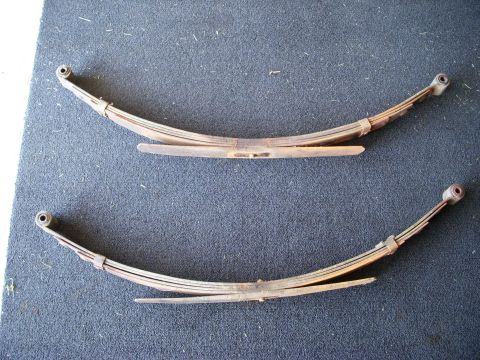 1977 Ford Bronco - Two leaf springs are shown against a dark, textured background. A watermark for Supermotors.net is visible in the lower right corner.