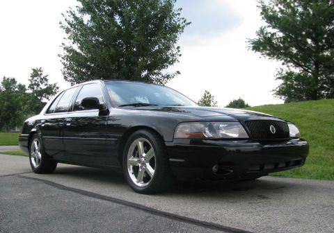 2003 Mercury Marauder - A black 2003 Mercury Marauder is shown from a three-quarter front view, parked outdoors on a paved surface with a grassy hill in the backgr…