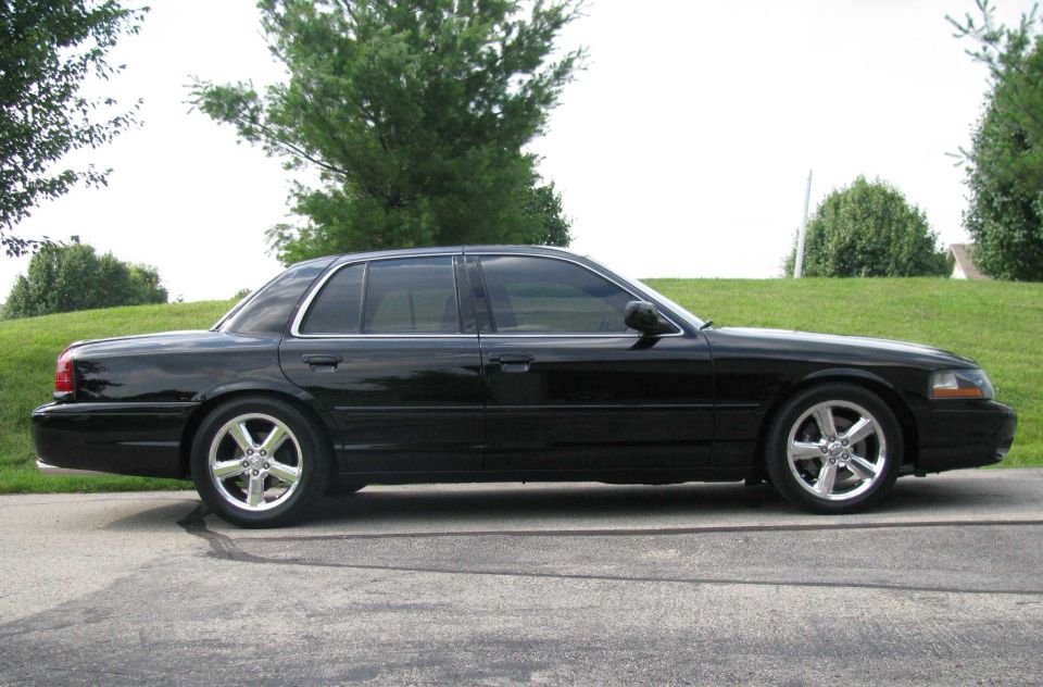 Black four-door sedan parked outdoors, side view.