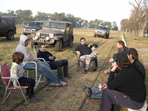 1996 Ford Explorer - Several off-road vehicles are parked in a grassy field while a group of people relax and socialize.