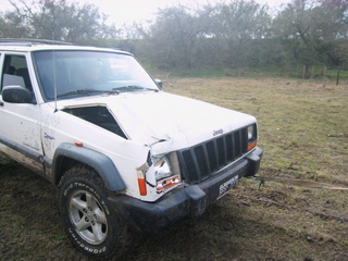1996 Ford Explorer - This white Jeep Cherokee has significant damage to its front end and hood.