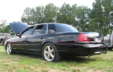 2003 Mercury Marauder - A black 2003 Mercury Marauder is shown from the rear 3/4 angle with its hood open, parked on grass at an outdoor event.