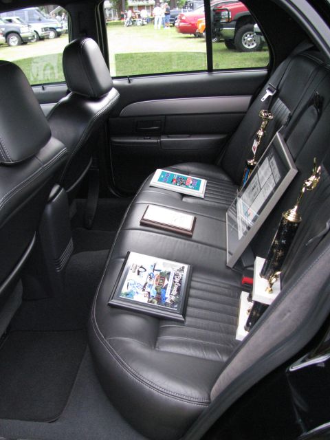 2003 Mercury Marauder - Car interior with trophies and framed photos on the back seat; other vehicles seen outside.