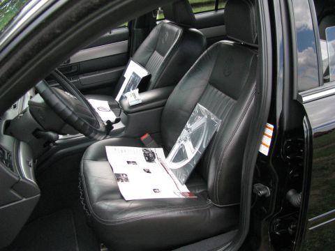 2003 Mercury Marauder - The interior of a car shows black leather seats with papers and a spare wheel placed on them.