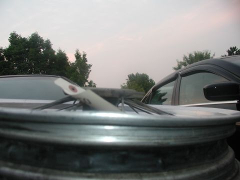 2001 Kawasaki KL650-A18 KLR650 - A close-up view of a motorcycle wheel with a white tag attached, with another vehicle visible in the background.