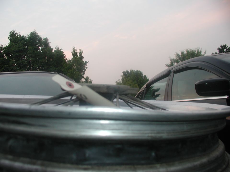 Close-up of a bare spoked wheel rim with a spoke tool across the hub outdoors
