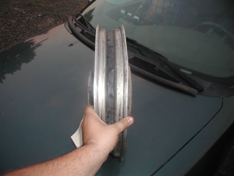2001 Kawasaki KL650-A18 KLR650 - A person holds a motorcycle wheel rim in front of a car's windshield.