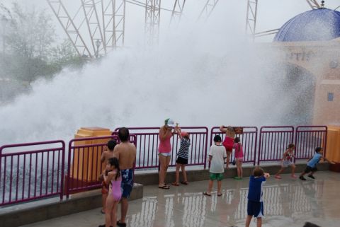 1996 Ford Bronco - People gather to watch a powerful wave surge at a water park attraction, with a large structure and dome visible in the background.