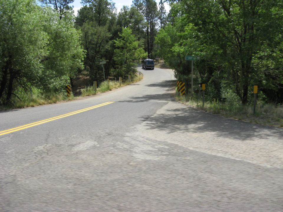 RV driving up a tree-lined road with a street sign that says 'Clement Dr'