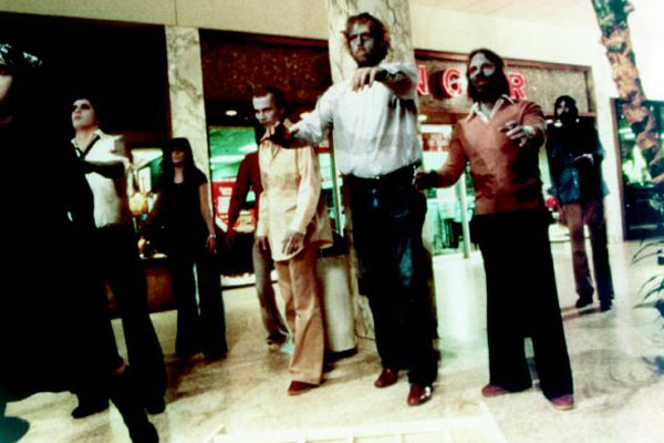 Group of people walking in a mall, some with outstretched arms