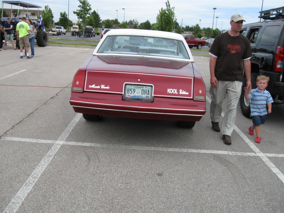 Red 1980 Chevrolet Monte Carlo rear view, white roof, Kool Edition badge. Man and child walk past