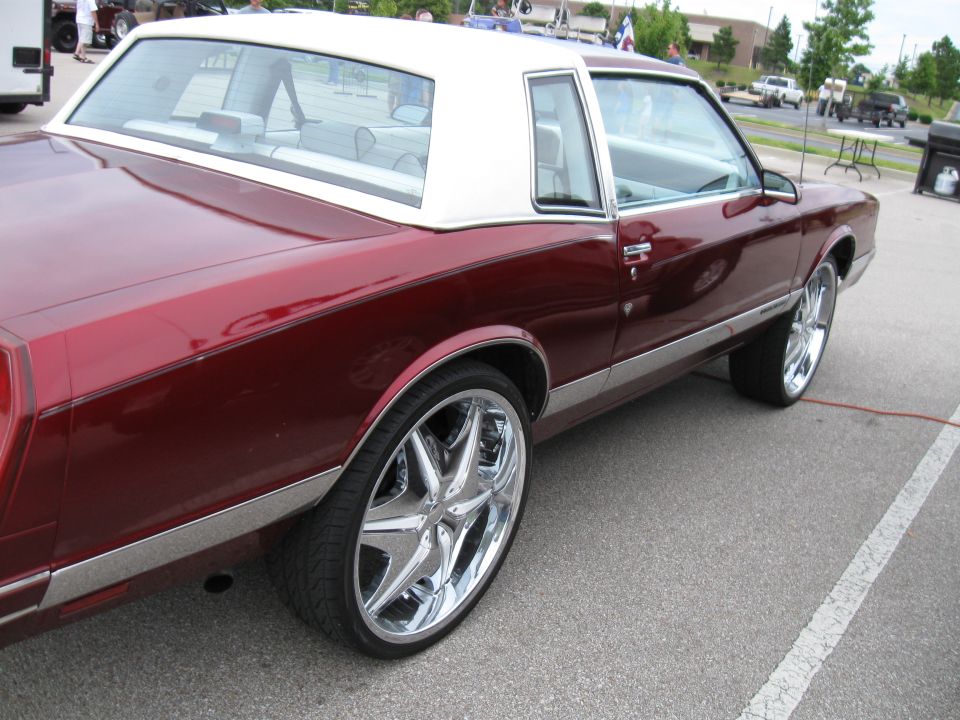 Maroon coupe with a white vinyl roof and chrome rims, seen from the rear quarter angle