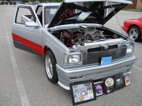 1994 Ford Bronco - A custom pickup truck with its hood open, displaying its engine and several awards at a car show.
