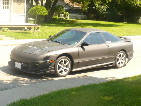 1993 Ford Probe - A gray 1993 Ford Probe is parked on the side of a road in front of a house.