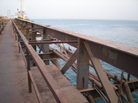 1981 Kenworth W900A - Industrial pier structure with metal framework and pipes against a backdrop of the sea.