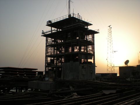 1981 Kenworth W900A - A tall radio tower and an unfinished building are silhouetted against a hazy sunset.