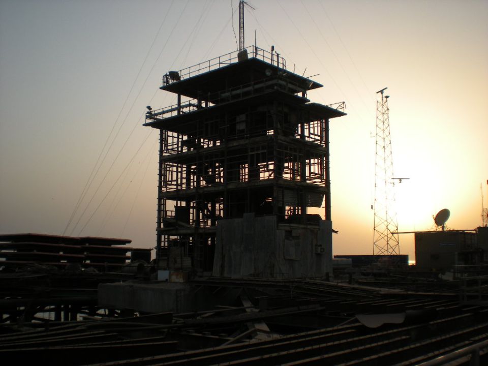 Radio tower and multi-story structure against sunset sky