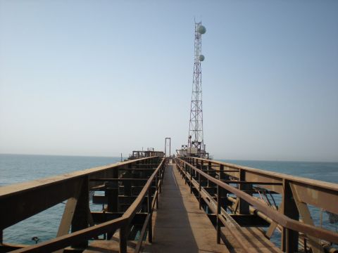 1981 Kenworth W900A - A long pier extends out over the water, leading to a communication tower against a clear sky.