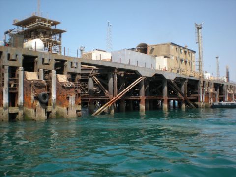 1981 Kenworth W900A - A view of a large, weathered industrial pier structure extending over the water under a clear blue sky.