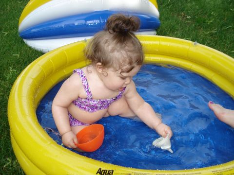 2000 Ford Crown Victoria - A baby enjoys a summer day playing in a kiddie pool with toys.