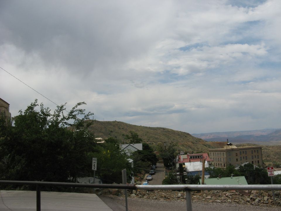 View of a town on a hillside with a large building on the right and a road winding through it