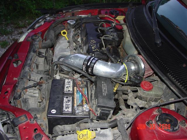 Red engine bay with aftermarket intake and visible battery