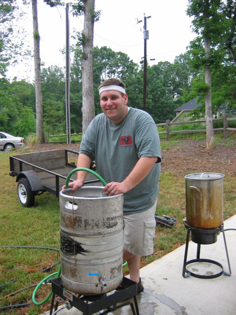 1985 Ford LTD Crown Victoria - A man is preparing to brew something outdoors, with a keg and a large pot visible.