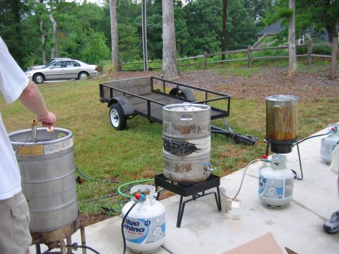 1985 Ford LTD Crown Victoria - A silver sedan is parked on the grass next to a trailer and outdoor cooking equipment.