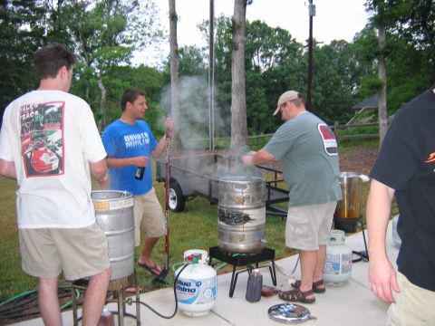 1985 Ford LTD Crown Victoria - Outdoor beer brewing scene with three men, kegs, and propane tanks. One man's shirt has a car graphic.