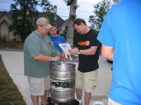 1985 Ford LTD Crown Victoria - A group of men are engaged in a brewing process outdoors, with a large keg as the central focus.