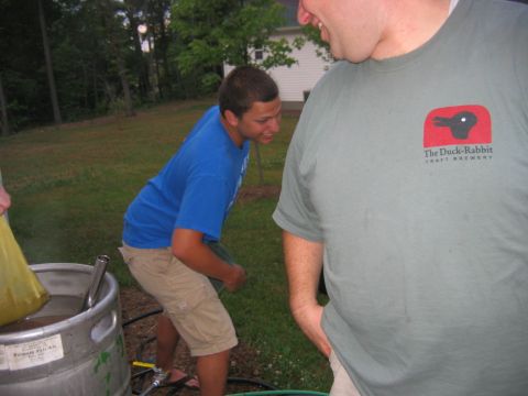 1985 Ford LTD Crown Victoria - Outdoor beer brewing activity with two individuals and a large metal keg.