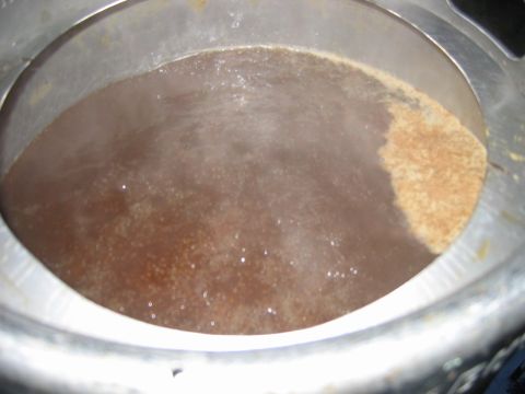 1985 Ford LTD Crown Victoria - A close-up view of wort being brewed, showing the liquid and some sediment.