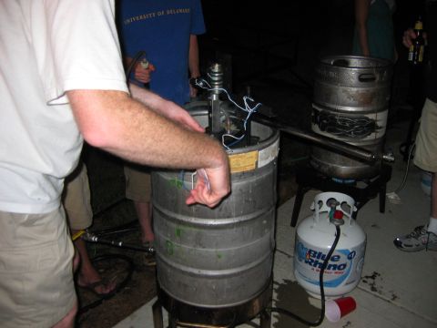 1985 Ford LTD Crown Victoria - A propane tank and tubing are connected to a keg setup, with people in the background.