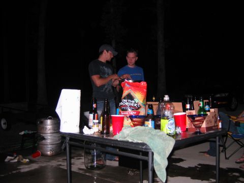 1985 Ford LTD Crown Victoria - An outdoor gathering with food and drinks is set up on a table at night.