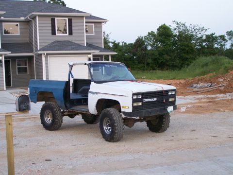 1975 Chevrolet Blazer - This lifted pickup truck is parked in front of a new house with construction materials visible in the background.