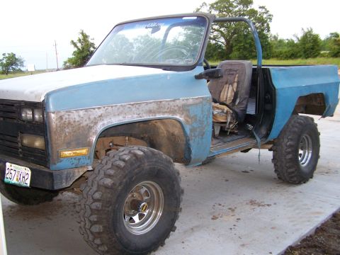 1975 Chevrolet Blazer - This modified pickup truck displays significant wear and tear, with a two-tone paint scheme and large off-road tires.
