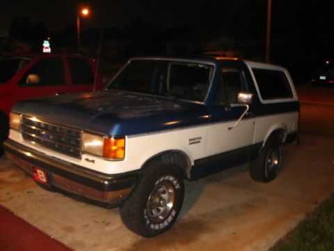 1991 Ford Bronco - Two-tone 1991 Ford Bronco parked outside at night, with another vehicle to its left.