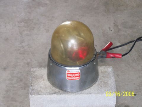 1998 Ford Crown Victoria - A close-up of a rotating beacon light, showing its amber dome and red bulb, connected to a power source.