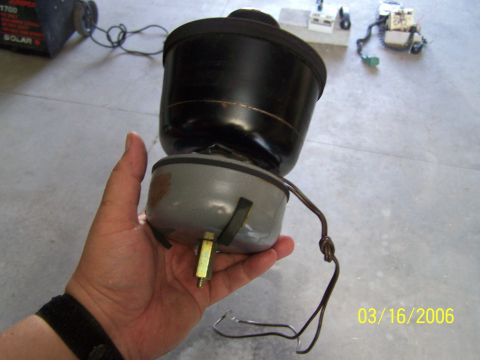 1998 Ford Crown Victoria - A hand holds an automotive part, possibly a filter or sensor, with wires connected. The background shows a concrete floor and other electro…