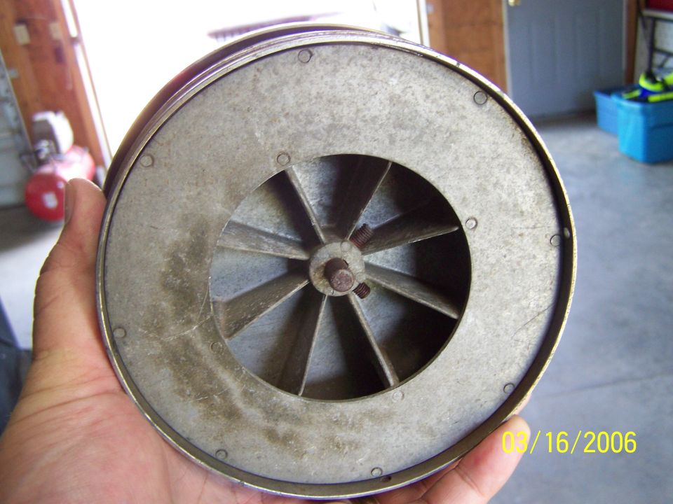 Blower fan held in hand, showing metal blades and a date stamp