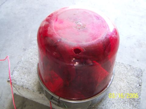 1998 Ford Crown Victoria - A red emergency light, possibly for a vehicle, shows signs of damage and a date stamp of 03/16/2006.