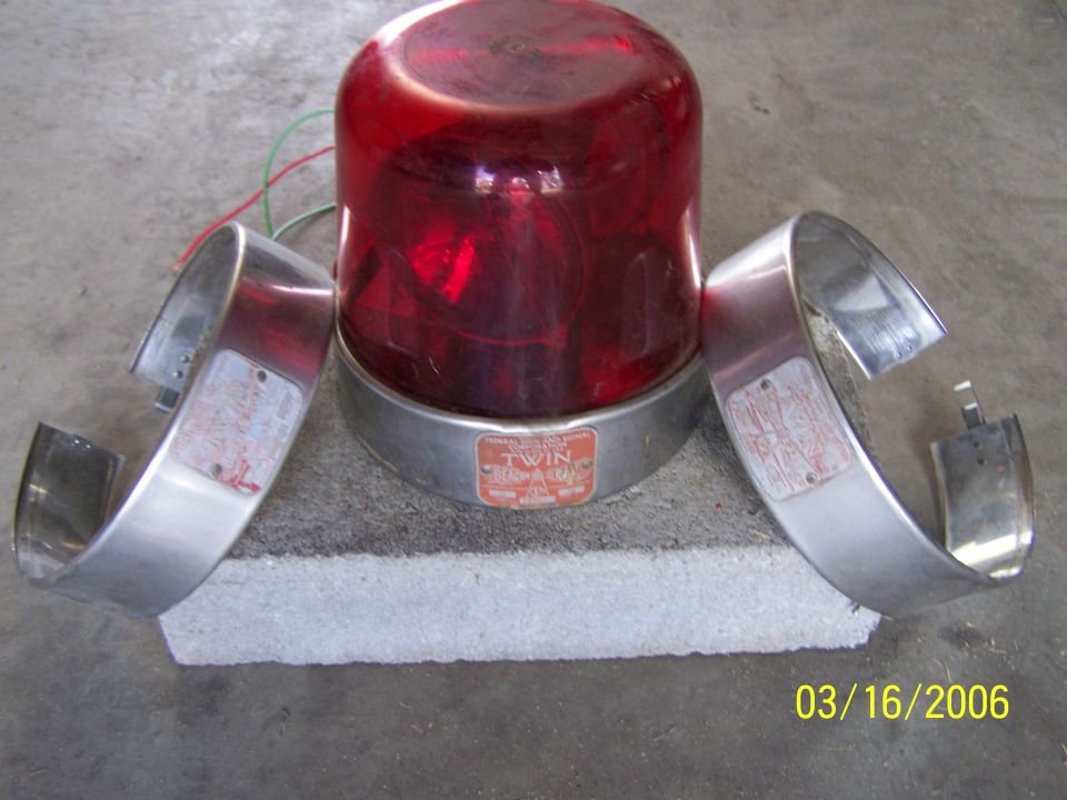 Red emergency light with two chrome rings, one on each side. A label on the light base says "TWIN"