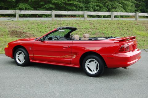 2001 Ford Crown Victoria - Red convertible parked on asphalt with a wooden fence and trees in the background.