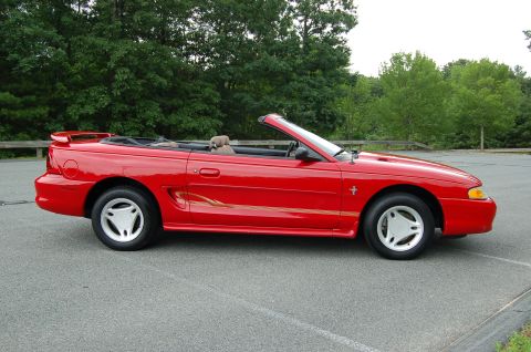 2001 Ford Crown Victoria - A red convertible with a gold stripe and spoiler is parked on asphalt.
