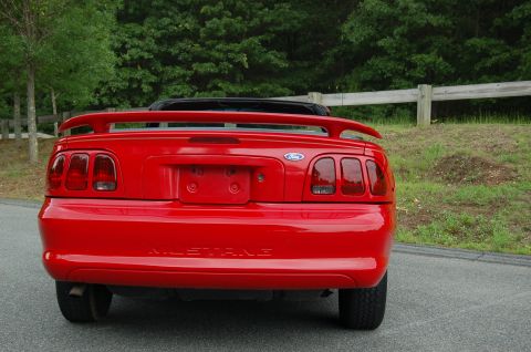 2001 Ford Crown Victoria - Rear view of a red Ford Mustang convertible, showing its distinctive taillights and spoiler.