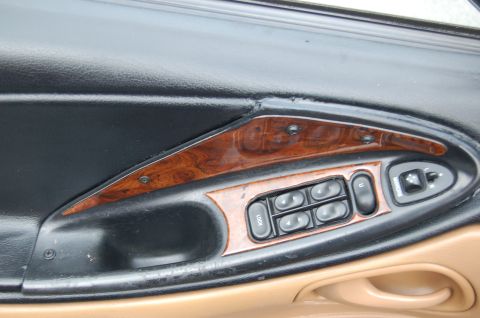2001 Ford Crown Victoria - Close-up of a car's interior door panel, showing power window controls and wood grain trim.