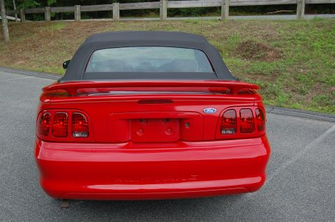 2001 Ford Crown Victoria - Rear view of a red convertible with a black top parked on asphalt.