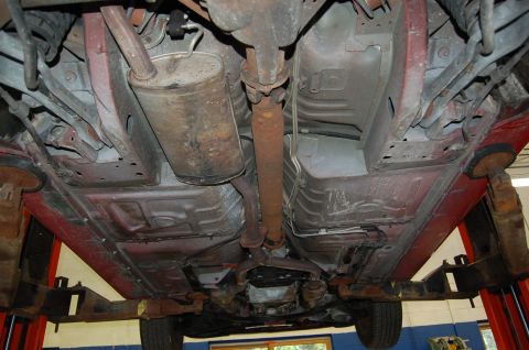 2001 Ford Crown Victoria - Underside view of a red vehicle on a lift, revealing the exhaust system, driveshaft, and suspension components.
