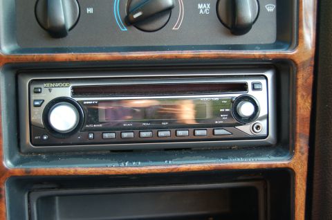 2001 Ford Crown Victoria - Car interior showing a Kenwood stereo unit and climate controls, surrounded by wood-grain trim.